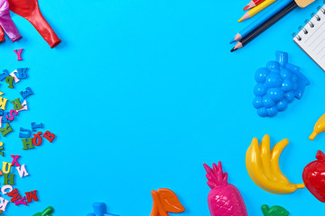 Blue background with childrens plastic toys, pencils