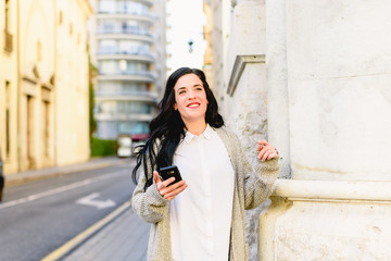 Young woman laughing holding her smartphone, happy to receive good news.