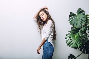 Young beautiful girl model Asian brunette with long hair posing in Studio with tropical plant on isolated background