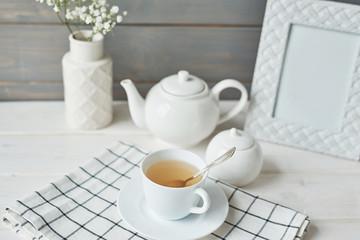 Beautiful bright tea set up. White ceramic tea pots and tea ingredients, on top of the white table. Copy Space. Spring Greeting Card Template. Cup of tea on table. Kitchen utensils