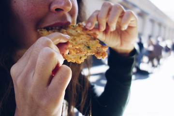 Woman eating tortillita de camarón (shrimp tortillita). Typical tapa of Cadiz, Andalusia, Spain