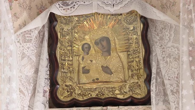 An icon depicting the Kazan Icon of the Mother of God, decorated with a towel with a bedspread in a wooden house in the red corner. Rushnik. Russian tradition.
