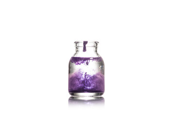 Studio shot of glass jar with water and purple splash isolated on white