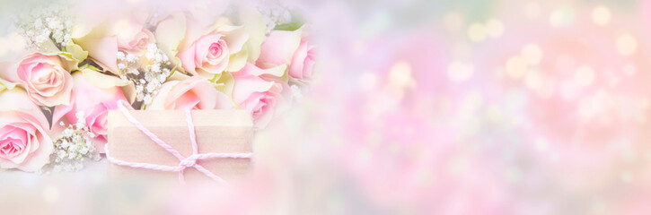 Pink roses and gift in front of pastel background