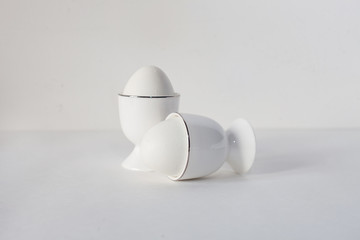 Minimalistic white eggs in a two stand for the egg on a white background.