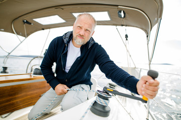 Mann kurbelt an Winsch auf einem Segelboot