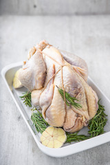 Uncooked guinea fowl in white baking dish with garlic and rosemary