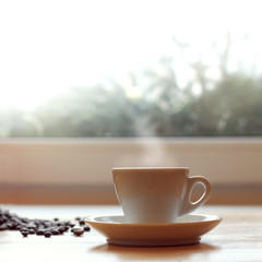 warming hot drink. white coffee cup on the table by the window