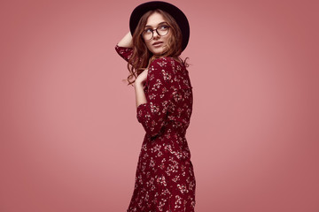 Elegant glamor hipster girl in red fashion dress, black hat and glasses