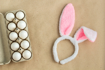 Top view of bunny ears easter holiday accessory and white egg on rustic background