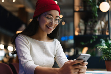 Portrait of happy Korean woman using mobile phone, download application for online shopping with...