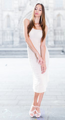 portrait of young  female in sexually ivory midi gown standing in town