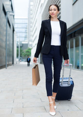 Businesswoman in suit with suitcase is going to the hotel