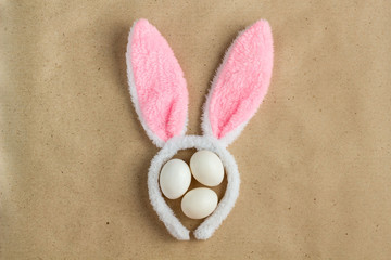 Top view of bunny ears easter holiday accessory and white egg on rustic background