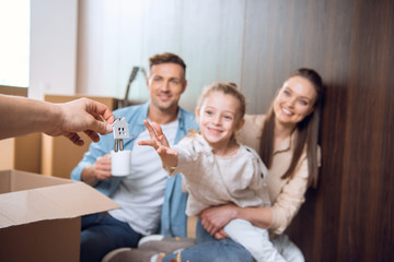 selective focus of house shaped key chain with smiling kid sitting near parents on background