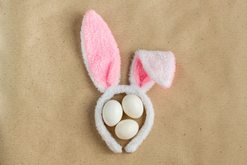 Top view of bunny ears easter holiday accessory and white egg on rustic background