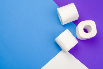 Rolls of unfolded toilet paper on a blue background. Flat lay, top view