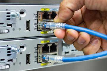 Hand of man holding The network cables to connect SFP module port in the Datacenter room, concept Communication technology