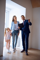 handsome broker showing room while standing near attractive woman and kid