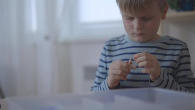 Little preschooler kid boy sitting at table and sculpting from plasticine.