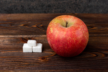 Cubes of sugar in apple on wooden background.