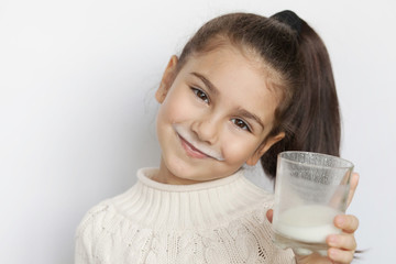Happy cute child girl drinking yogurt on white background. Whiskers from yogurt