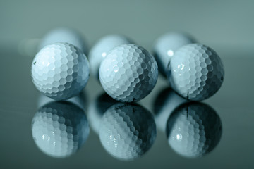 White golf balls in a row reflecting on a mirror