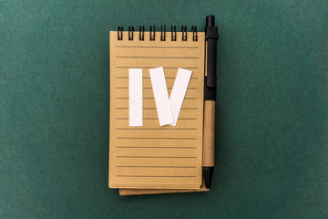 Notebook front with pen and white four Roman number on green background. Spiral notepad on a table....