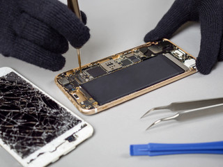 Technician or engineer disassembling components broken smartphone for repair or replace new...