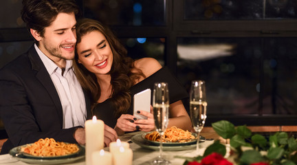 Cute couple using smartphone in restaurant