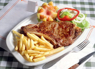 Plato con un chuletón a la plancha con patatas fritas y ensalada