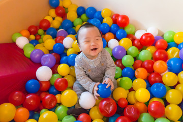 Fototapeta na wymiar Asian baby playing in colorful ball pool