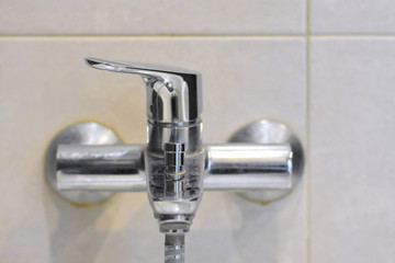 Dirty chrome faucet with selective focus on blurred background. Steel bathroom faucet with dirty silver surface. Mold or fungus at the blurred bathroom wall. Stainless design shower 