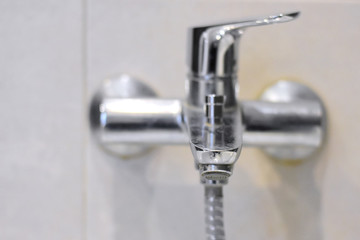 Dirty chrome faucet with selective focus on blurred background. Steel bathroom faucet with dirty silver surface. Mold or fungus at the blurred bathroom wall. Stainless design shower 