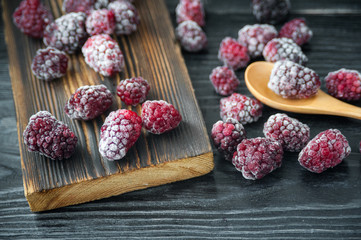 Frozen blackberry on dark wooden table..