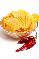 Bowl of potato chips with red hot pepper on white background