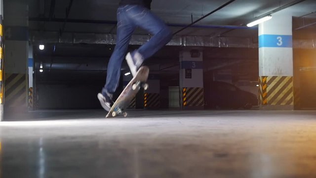 Underground parking lot. A young man skateboarding. Practicing complicated trick