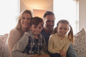 Obraz premium Happy family sitting together on sofa in living room at home