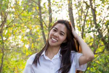 Portrait of asian college woman smiling in blur background witn sunset.