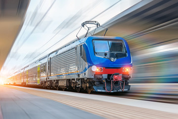 Railway station with head locomotive high speed commuter train with motion blur effect