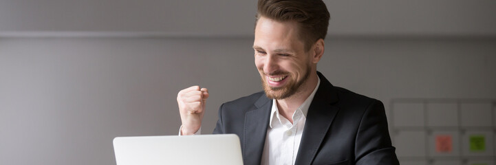 Horizontal photo happy businessman in suit sitting at desk look at laptop read receive great news...