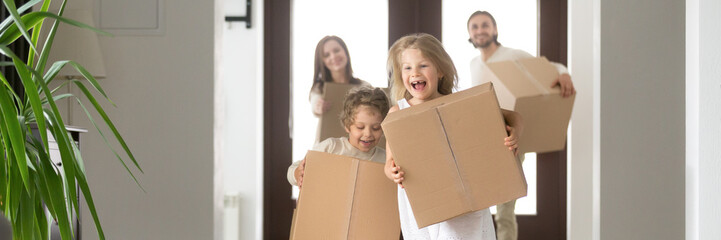 Horizontal photo happy family couple little children hold boxes belongings running into new house...