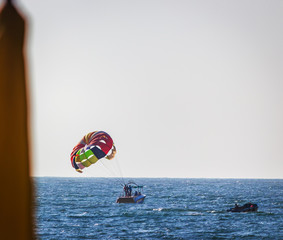 Parasailing water amusement - flying on a parachute behind a boat on a summer holiday by the sea in the resort in Goa India. Baga beach