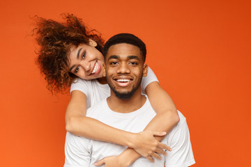 Young lovely african-american couple posing on orange background