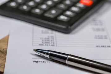 Ballpoint Pen and Calculator Lie on Business Signature Contract Document