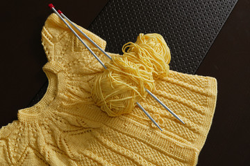 handmade knit, the knitting needles on a black background and yellow Orlon,