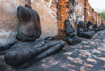 Headless Buddha Statues in a row near a brick wall in Buddhist Temple Wat Maha That, Ayutthaya historical park, Thailand.