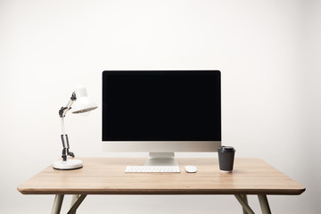workplace with lamp, coffee to go and desktop computer with copy space isolated on white
