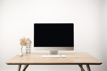 workplace with house model, dry flowers and desktop computer with copy space isolated on white