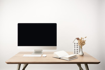 workplace with dry flowers, house model, notebook and desktop computer with copy space isolated on white